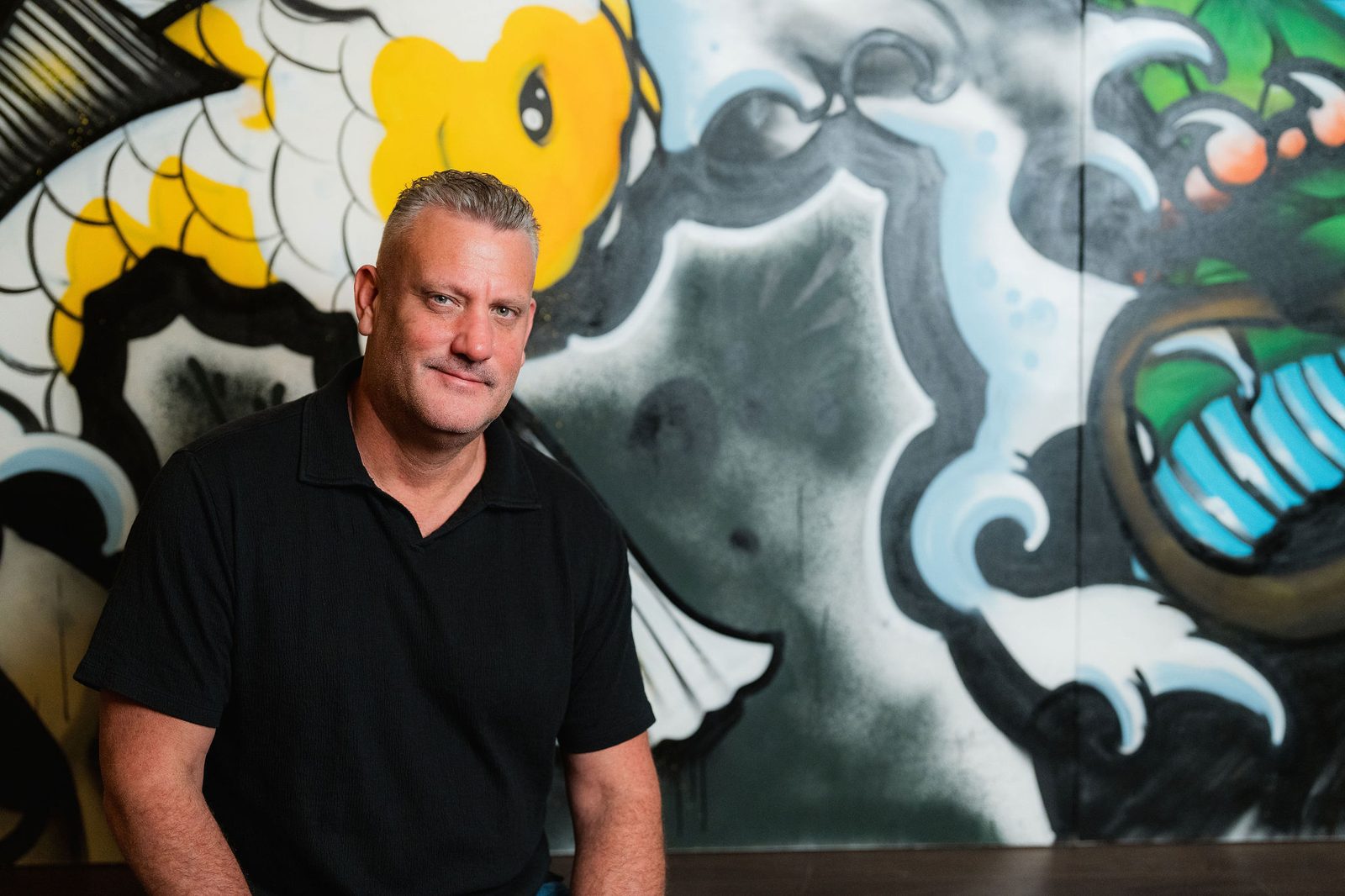 John Carswell of APEX Everett in front of the graffiti mural inside his restaurant